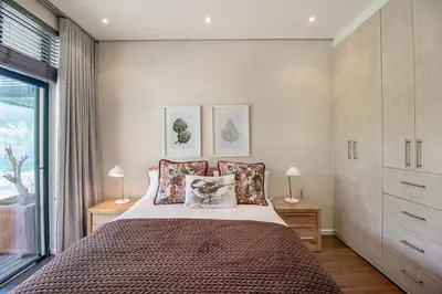 a bedroom with a bed with two lamps and a window at Bayhill Terrace 17 by CTHA in Cape Town