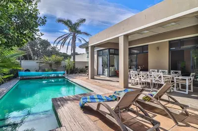 a house with a pool and two chairs and a table at Bayhill Terrace 17 by CTHA in Cape Town