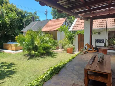 a backyard with a wooden table and a house at Garden City Summer in Cape Town