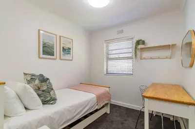 a small bedroom with a bed and a table at Chic, Cozy, Modern, Secure and Centrally Located in Cape Town
