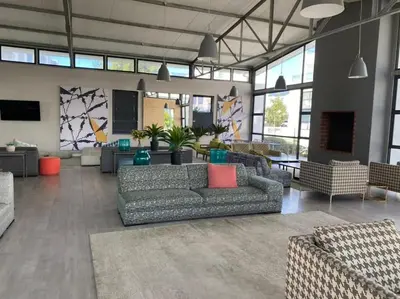 a living room with couches and tables and windows at Sundown Apartment in Cape Town