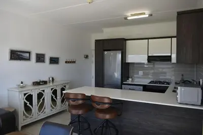 a kitchen with two bar stools and a counter at Sundown Apartment in Cape Town