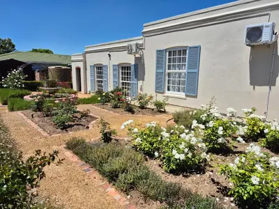 a garden in front of a house with flowers at Schoongezicht Guesthouse in Durbanville