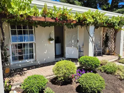 a house with a pergola with flowers and plants at Schoongezicht Guesthouse in Durbanville