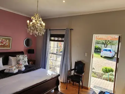 a bedroom with a bed and a chandelier at Schoongezicht Guesthouse in Durbanville