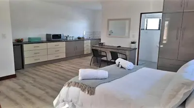 a bedroom with a large white bed and a kitchen at Hermanus reefs in Hermanus