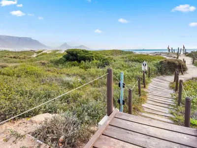 a stairway to the beach with people walking on the beach at Neptune Isle 9 in Cape Town