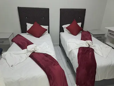 two beds with burgundy and white sheets and pillows at Abyssinia Guest House in Cape Town
