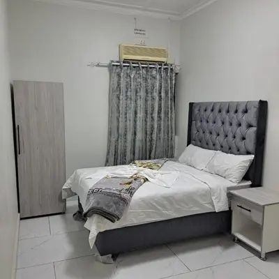 a bedroom with a large bed with a gray headboard at Abyssinia Guest House in Cape Town