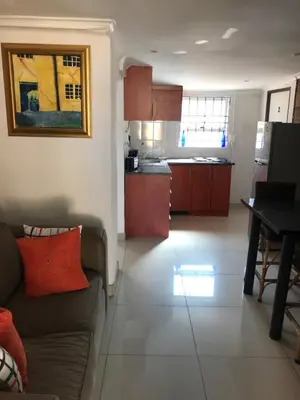a living room with a couch and a kitchen at MELJAA GROUP Guesthouse in Cape Town