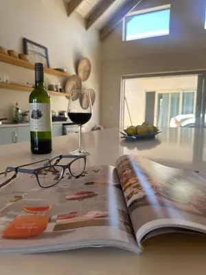 a bottle of wine and glasses sitting on top of a book at Sandown Synergy Lagoon House in Hermanus