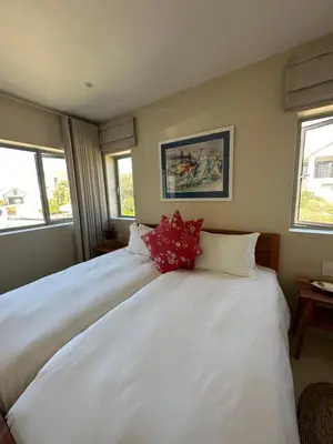 a large white bed in a room with windows at Sandown Synergy Lagoon House in Hermanus