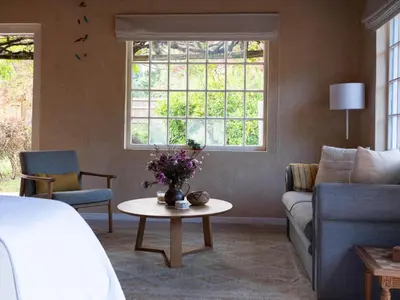 a living room with a couch and a table with flowers at Cape Weaver cottage in Greyton