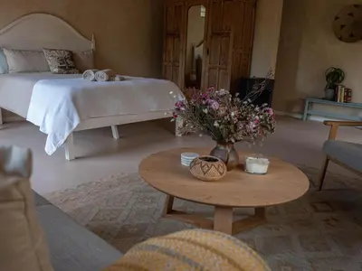 a bedroom with a bed and a table with flowers at Cape Weaver cottage in Greyton
