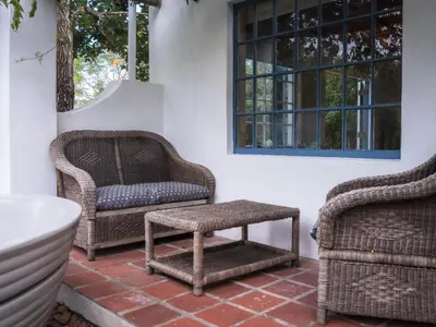 a patio with wicker chairs and a bath tub at Cape Weaver cottage in Greyton