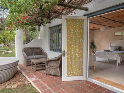 an open door to a patio with a tub at Cape Weaver cottage in Greyton