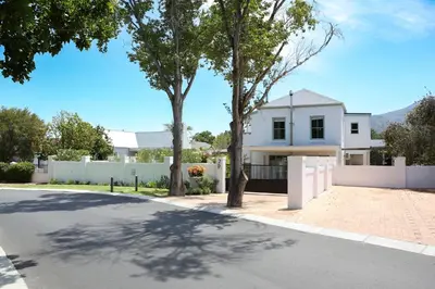 a white house with a white fence and trees at Largest one bed apartment & private pool in the Hoek in Franschhoek