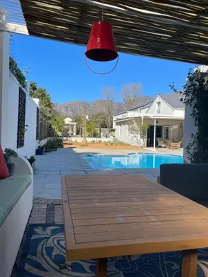 a patio with a wooden table and a pool at Largest one bed apartment & private pool in the Hoek in Franschhoek