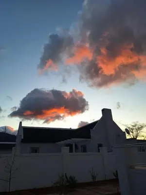 a sunset over a house with a white fence at Largest one bed apartment & private pool in the Hoek in Franschhoek