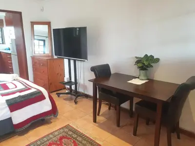 a dining room with a table and a television at Cape Cottage in Cape Town
