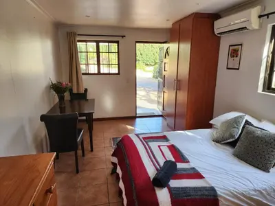 a bedroom with a bed and a desk and a table at Cape Cottage in Cape Town