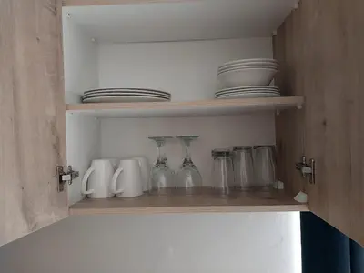 a shelf with glasses and plates on it at Neptune in Gordonʼs Bay