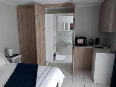 a bedroom with a bed and a bathroom with a sink at Neptune in Gordonʼs Bay