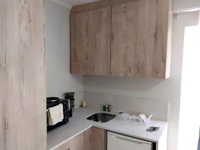 a kitchen with wooden cabinets and a sink at Neptune in Gordonʼs Bay