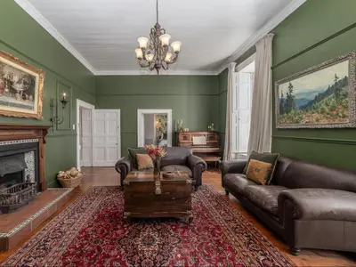 a living room with green walls and a chandelier at Nantes-vue in Paarl