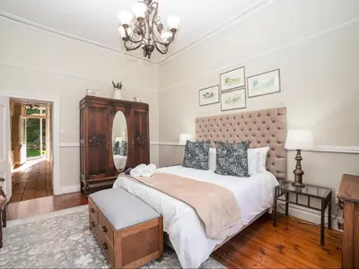 a bedroom with a large bed and a chandelier at Nantes-vue in Paarl