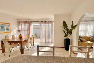 a dining room and living room with a table and chairs at 3 Bedroom Family Home with Pool in Cape Town
