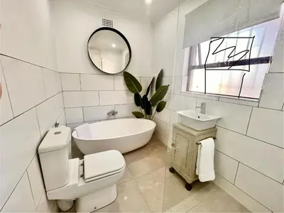a bathroom with a tub and a toilet and a sink at 3 Bedroom Family Home with Pool in Cape Town