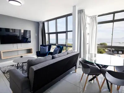 a living room with a couch and a table and chairs at St Tropez Beachfront 306 in Strand