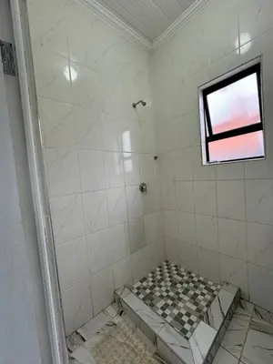 a bathroom with a shower with a tiled floor at Michu Guest house in Cape Town