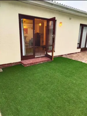 a yard with green grass in front of a house at Claremont Studio in Cape Town