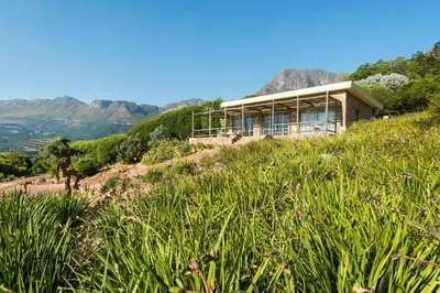 a house on a hill with mountains in the background at Amberg Country Estate in Paarl