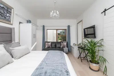 a white bedroom with a large bed and a couch at Platinum Haven Aparment in Milnerton in Cape Town