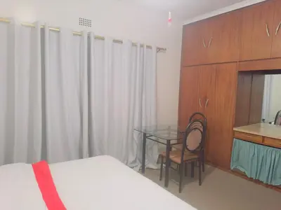 a bedroom with a bed and a glass table and a desk at Leisure Lodges selfcatering accommodation Parow in Cape Town