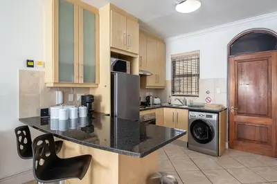a kitchen with a black counter top and wooden cabinets at Spacious 1 Bedroom Flat Church St Stellenbosch in Stellenbosch