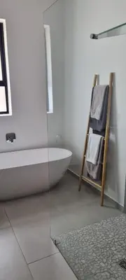 a bathroom with a bath tub and a bath rug at Somer House Guest Suites in Somerset West