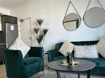a living room with two green chairs and a table at Luxury Stays in Cape Town