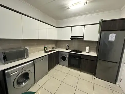 a kitchen with white cabinets and a washer and dryer at Luxury Stays in Cape Town