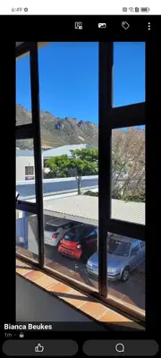 a window view of cars parked in a parking lot at Sea View Room in Gordonʼs Bay