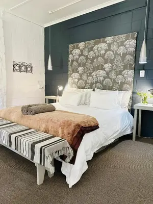 a bedroom with a large bed with a large headboard at Agapanthus garden cottage in Grabouw