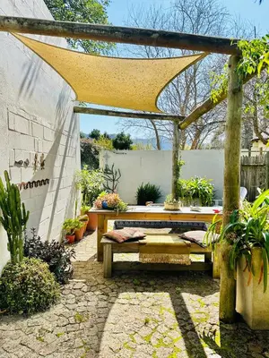 a patio with a wooden pergola and a wooden bench at Agapanthus garden cottage in Grabouw
