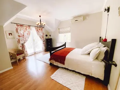 a bedroom with a large bed with a red blanket at Jonquil Guest Cottage in Franschhoek