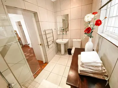 a bathroom with a vase of flowers on a table at Jonquil Guest Cottage in Franschhoek