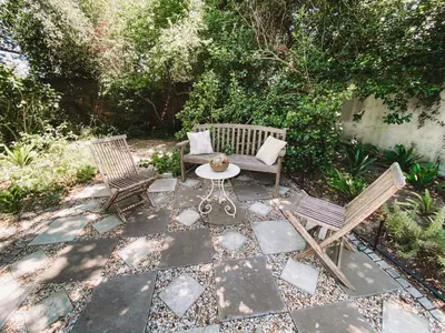 a patio with two chairs and a table and a bench at Jonquil Guest Cottage in Franschhoek