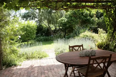 a wooden table and chairs in a garden at Jonquil Guest Cottage in Franschhoek