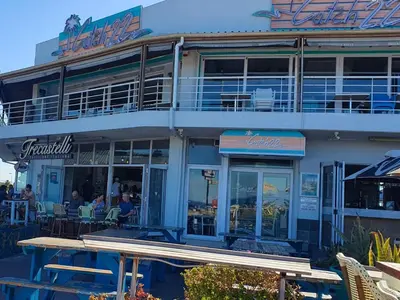a building with tables and chairs in front of it at Bloubergstrand Beachfront Apartment Witsand 101 in Cape Town